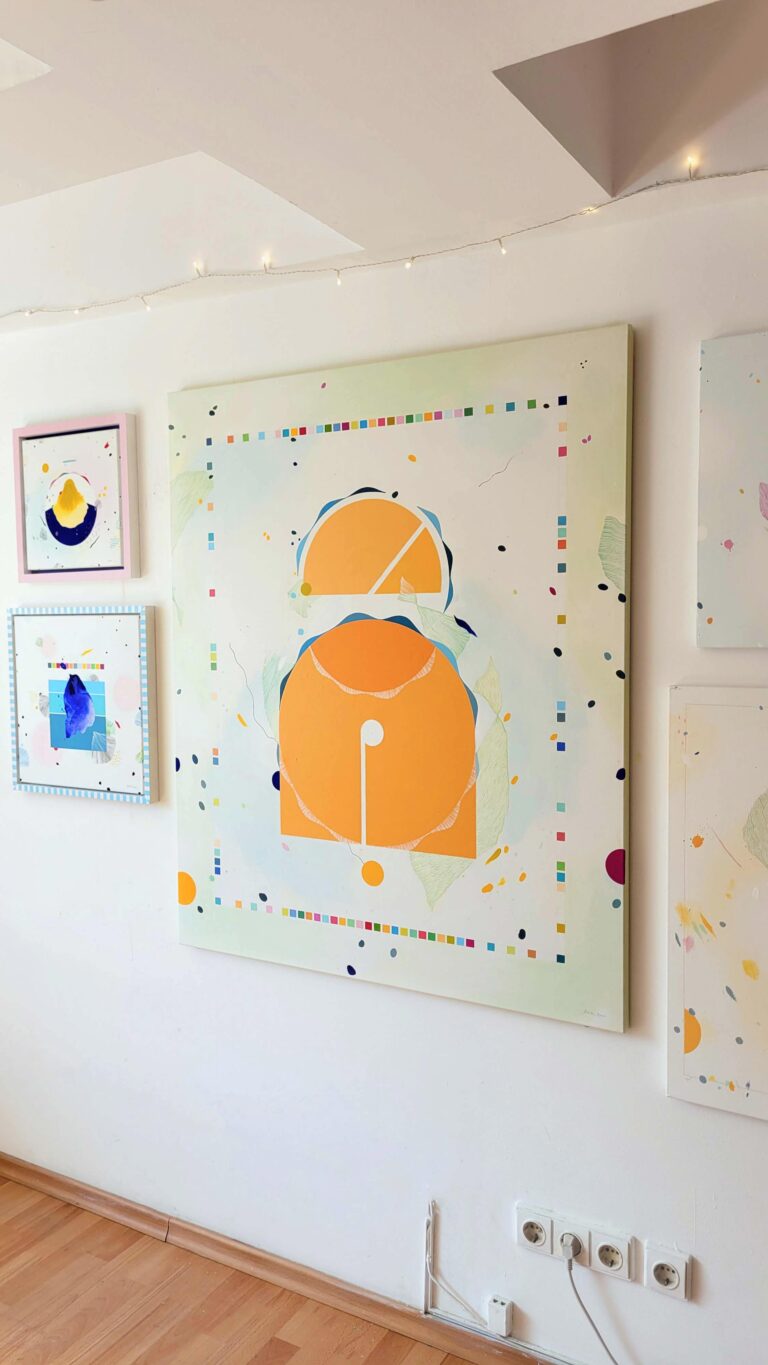 Minimalistinis abstraktus paveikslas ant drobės su geltonomis ir oranžinėmis geometrinėmis figūromis, pasteliniu fonu ir spalvingu dekoratyviniu rėmeliu.